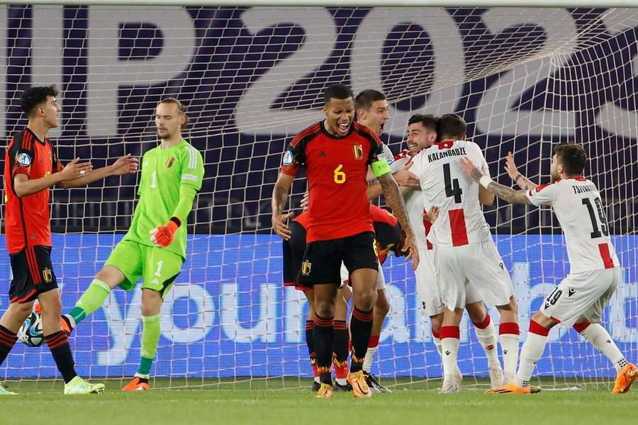 België's Aster Vranckx baalt flink terwijl de spelers van Georgië de 2-2 vieren