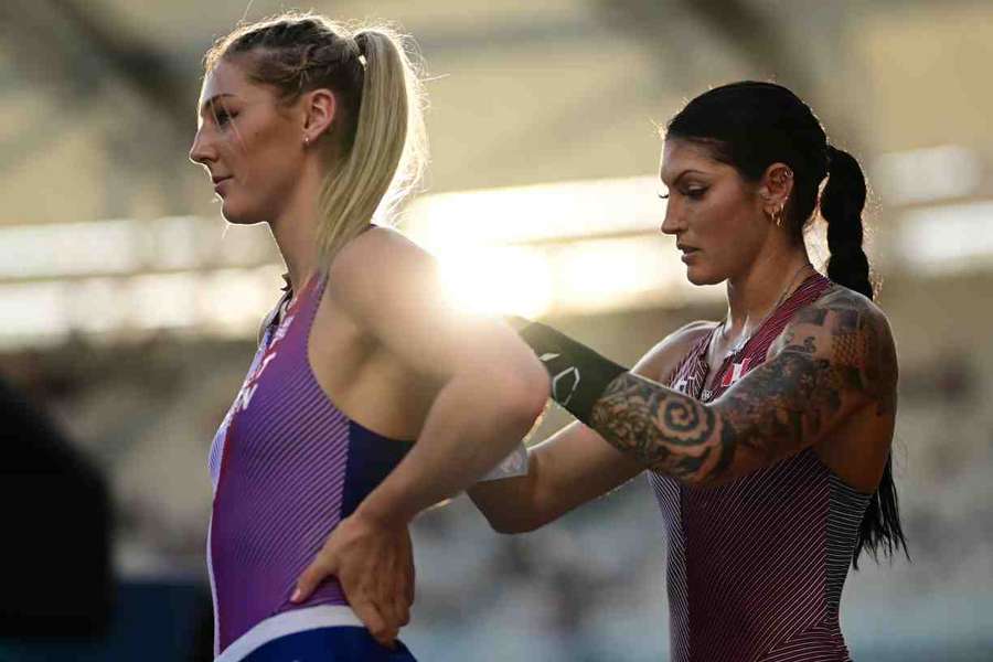 Canada's Anicka Newell pins the number onto the back of GB's Molly Caudery as they warm up ahead of the pole vault qualification