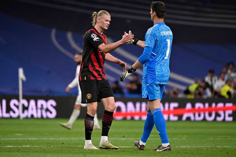 Manchester City striker Erling Haaland (L) greets Real Madrid goalkeeper Thibaut Courtois at the end of the match