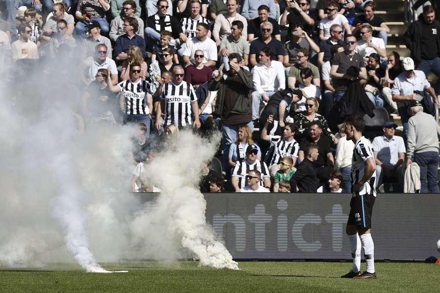 Heracles Almelo's Ajdin Hrustic looks on as supporters throw fireworks onto the pitch
