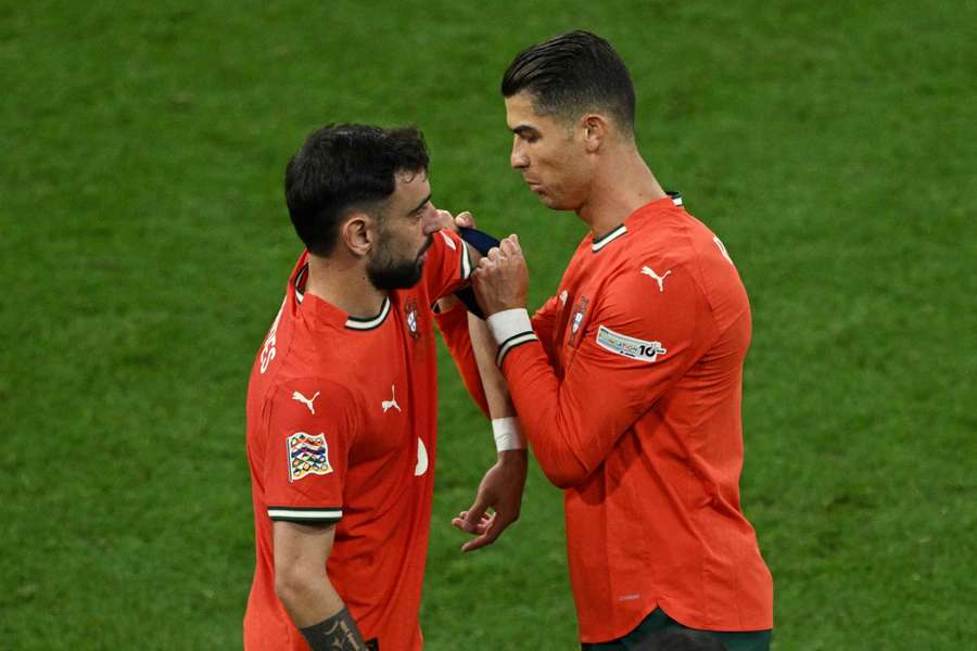 Cristiano Ronaldo (right) gives the captain's armband to Bruno Fernandes