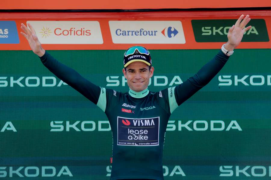 Wout van Aert celebrates while wearing the points jersey on the podium after winning stage seven