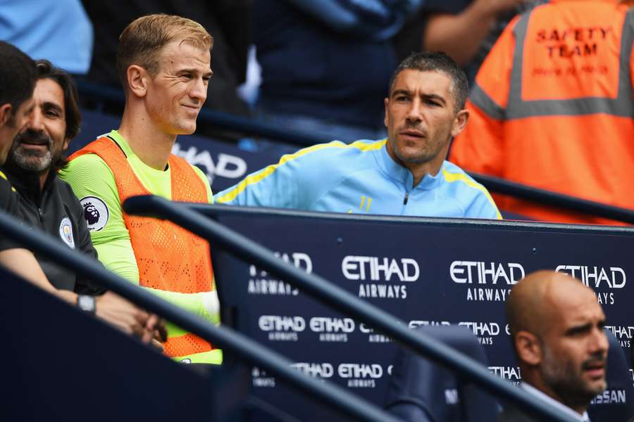 Joe Hart sits on the Man City bench behind Pep Guardiola in 2016