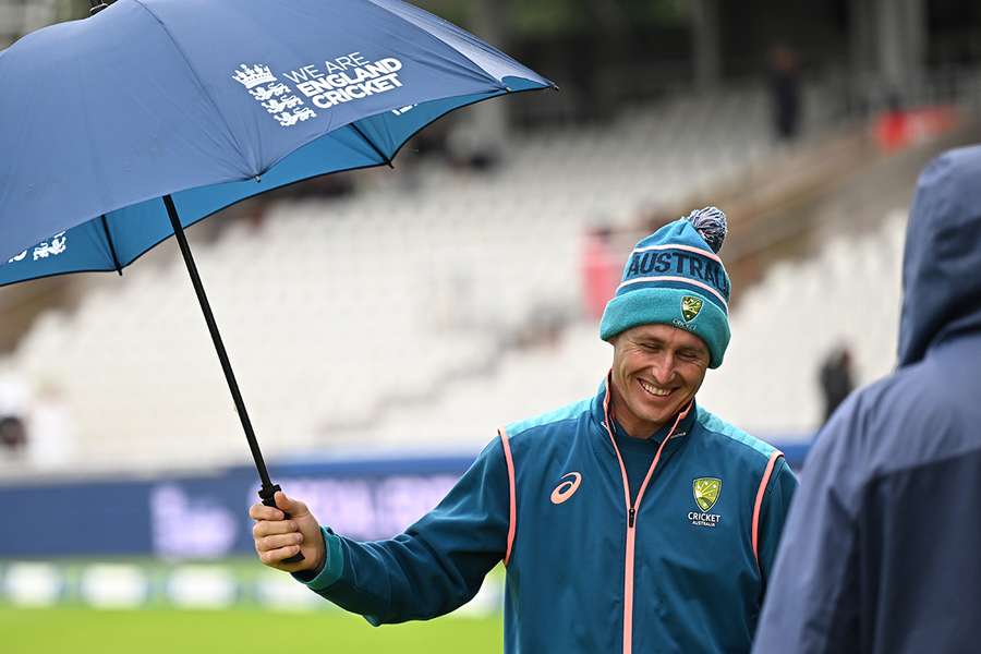 Australia's Marnus Labuschagne stands under an umbrella in the rain