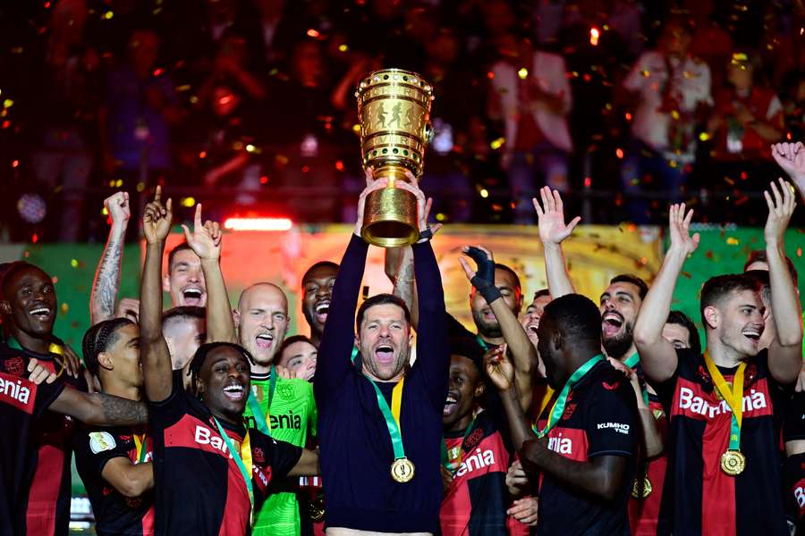 Xabi Alonso lifts the German Cup flanked by his Leverkusen players