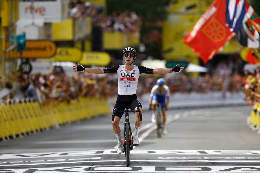 Adam Yates lifts his arms aloft in Bilbao with brother Simon behind him