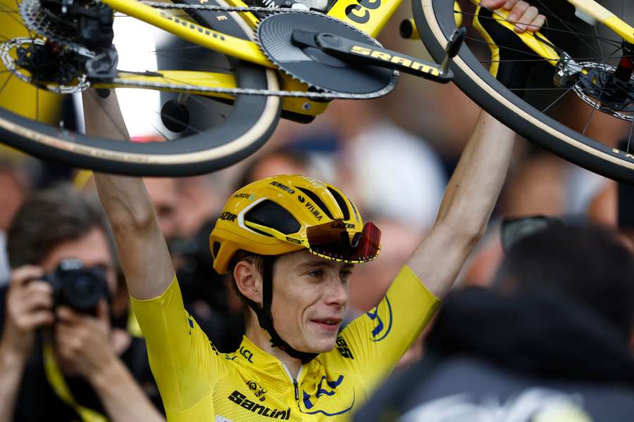 Jonas Vingegaard lifts his bike to celebrates winning the Tour de Franc