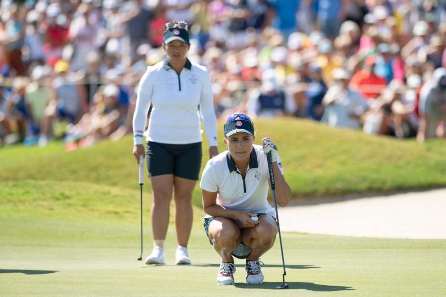 US team's golfer Lexi Thompson (R) crouches to look at the hole