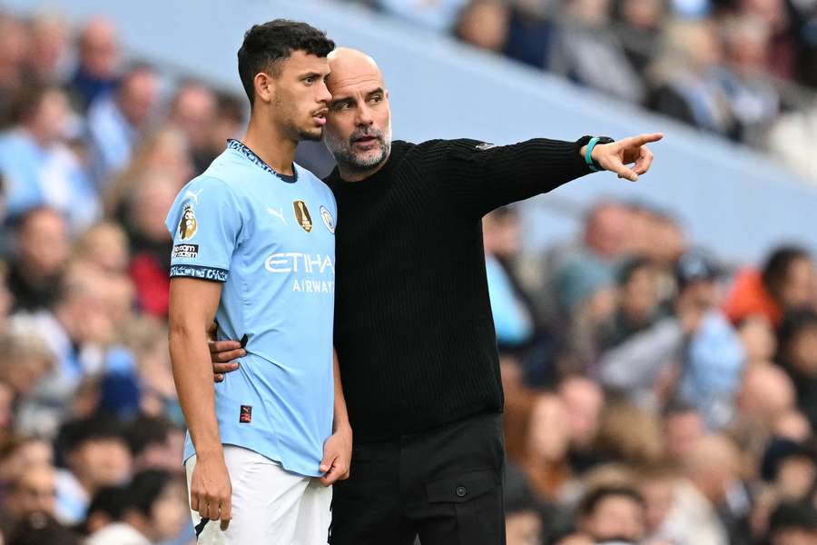 Manchester City's Spanish manager Pep Guardiola (R) gives instructions to Portuguese midfielder #27 Matheus Nunes 