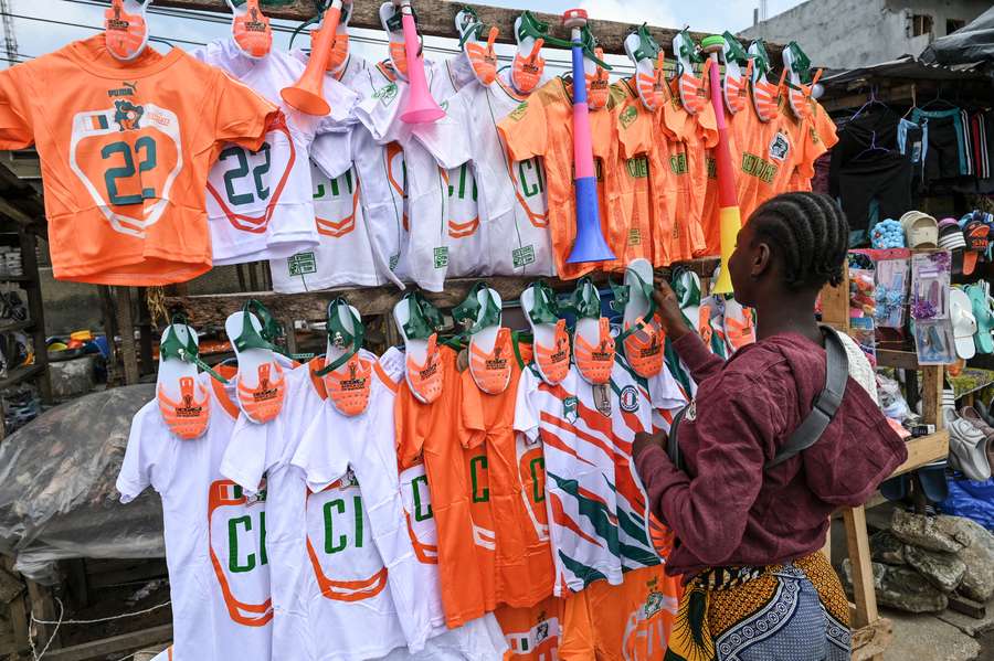 A shopkeeper selling Ivory Coast football kits waits for customers