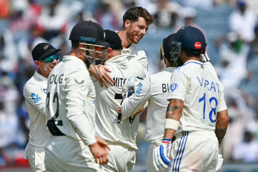 New Zealand's Mitchell Santner (C) celebrates with teammates after taking the wicket of India's Virat Kohli