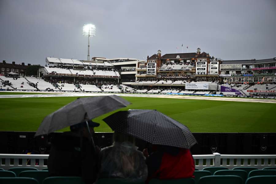 Fans sit under umbrellas as the rain falls on day one of the Test between England and South Africa.