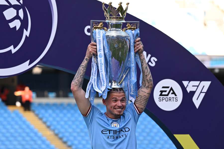 Manchester City's English midfielder Kalvin Phillips poses with the Premier League trophy