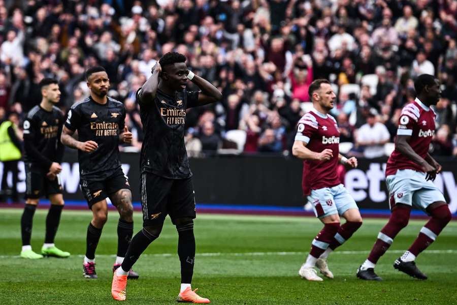 Arsenal winger Bukayo Saka (C) reacts after missing a penalty against West Ham