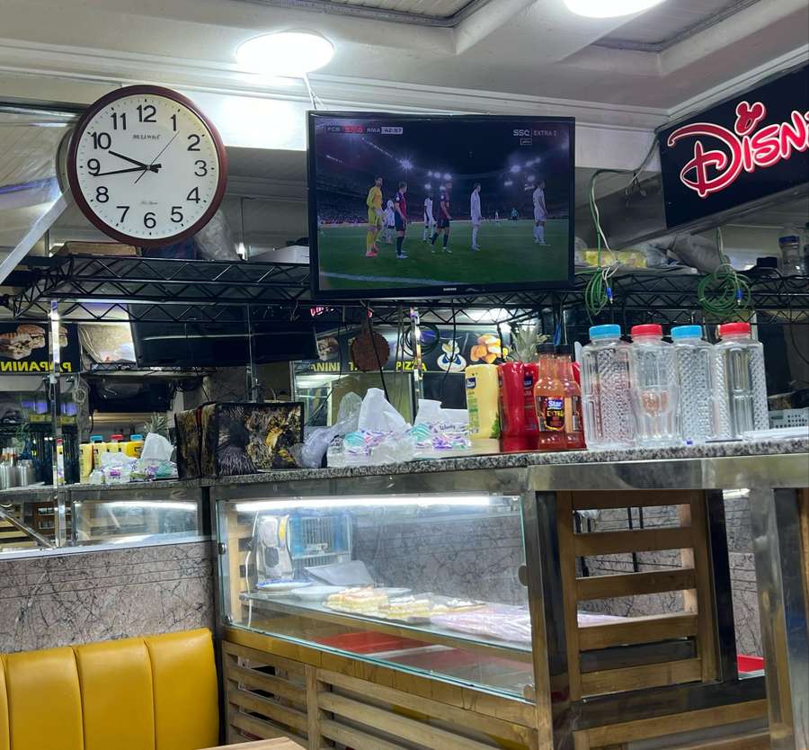El partido se emite en un local de comida rápida. El partido se emite en un local de comida rápida.