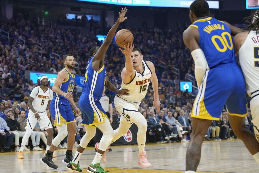 Nikola Jokic probeert langs Draymond Green te schieten