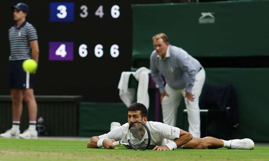 Serbia's Novak Djokovic lies on the lawn after slipping on the grass