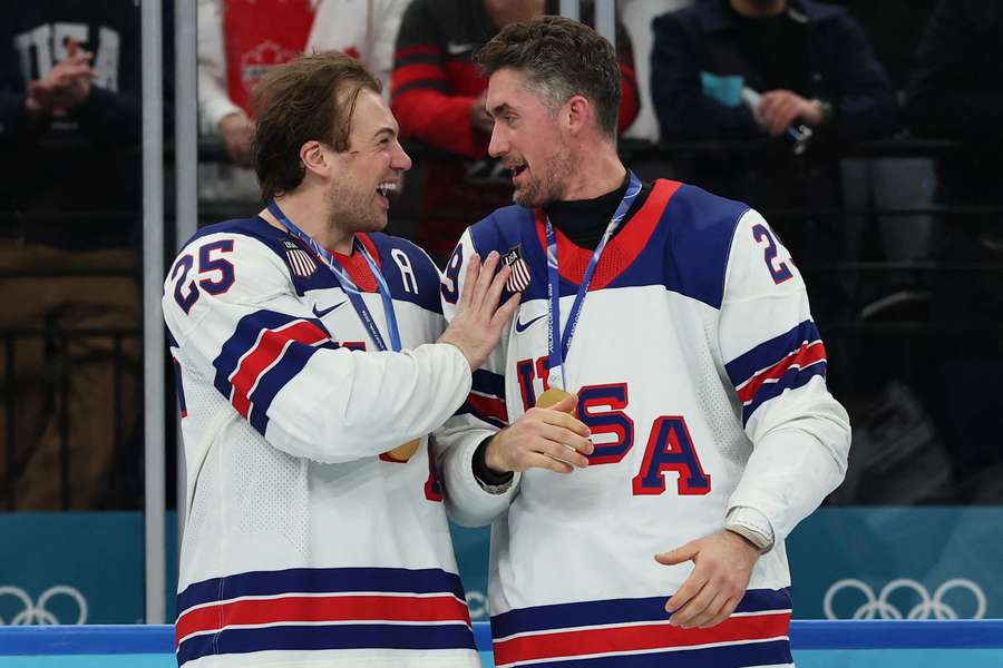 Brock Nelson (vpravo) prijíma gratulácie od Charlieho McAvoya po triumfe na OH 2026.