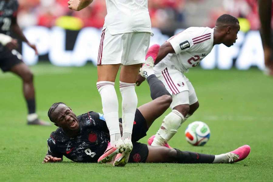 Ismael Kone (L) of Canada falls down after getting tackled by Qatar's Assim Madibo 