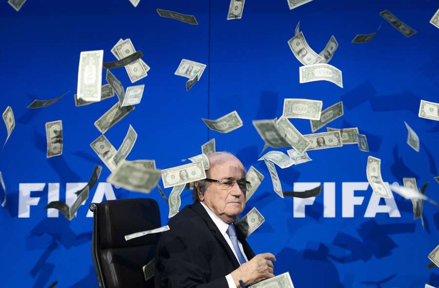 FIFA President Sepp Blatter sits as he gets showered with fake dollar bills by British comedian Simon Brodkin FIFA President Sepp Blatter sits as he gets showered with fake dollar bills by British comedian Simon Brodkin