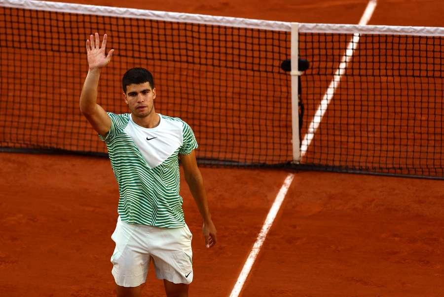 Carlos Alcaraz waves to the crowd after securing passage into the second round