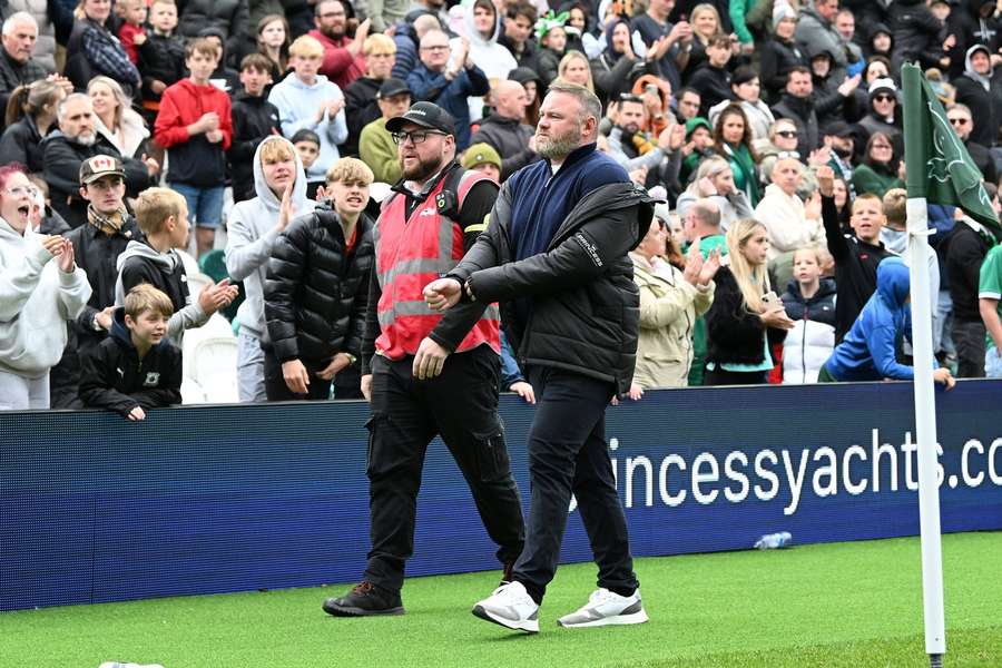 Rooney verlaat het veld met een beveiligingsmedewerker  