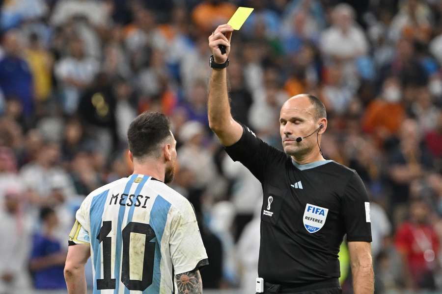 Spanish referee Antonio Mateu Lahoz shows a yellow card to Lionel Messi