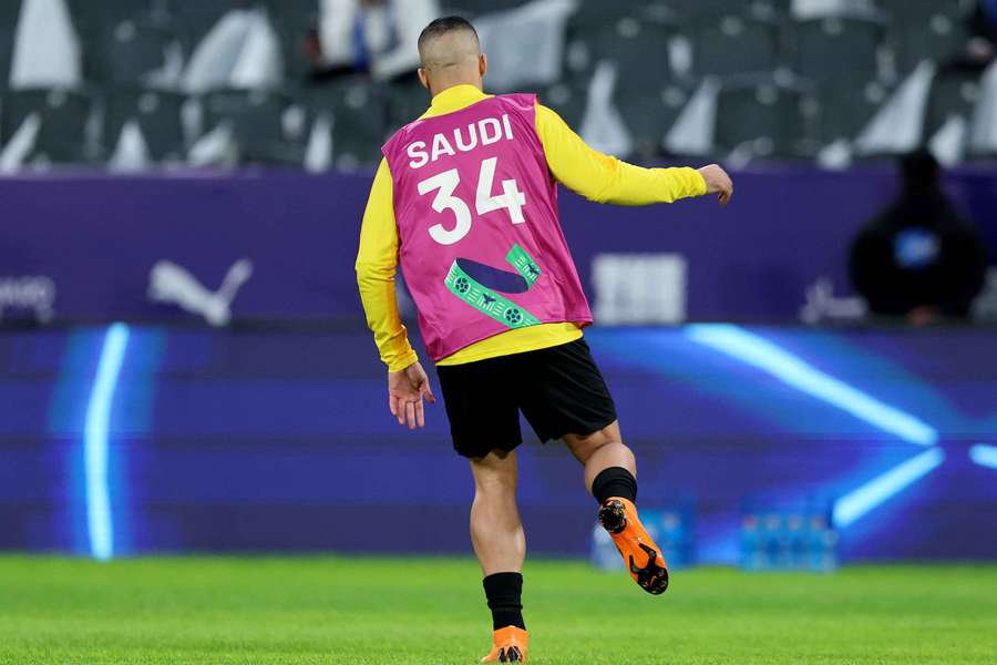 Abderrazak Hamdallah, del Al Ittihad, calienta con una camiseta promocional de la candidatura de Arabia Saudí 2034