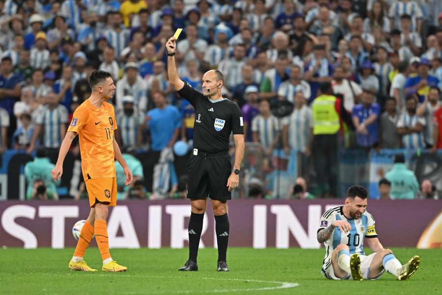 Spanish referee Antonio Mateu Lahoz shows a yellow card to Netherlands midfielder Steven Berghuis