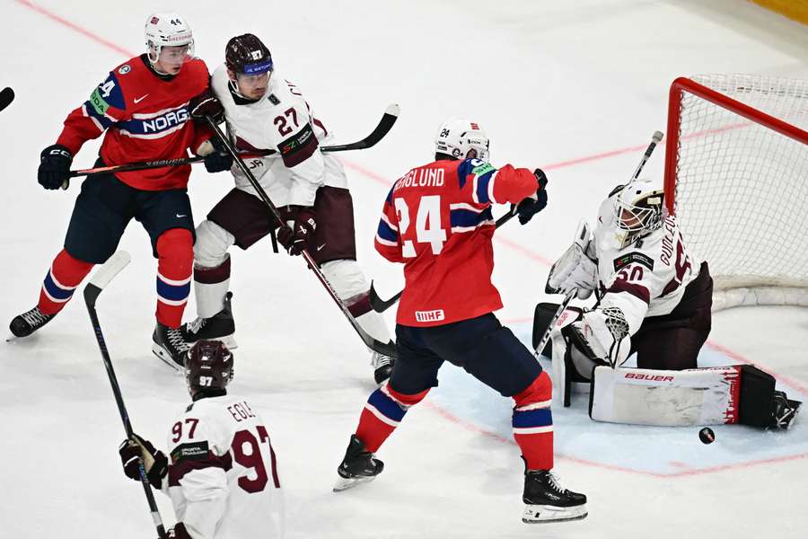 Latvia's goalkeeper Kristers Gudlevskis (R), Latvia's defender Oskars Cibulskis (2L) and Latvia's forward Haralds Egle vie for the puck Latvia's goalkeeper Kristers Gudlevskis (R), Latvia's defender Oskars Cibulskis (2L) and Latvia's forward Haralds Egle vie for the puck