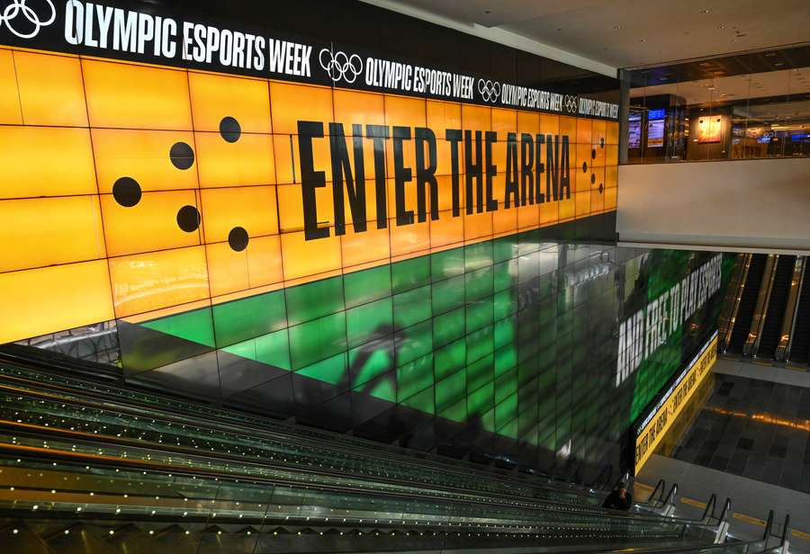 This photo taken on June 19, 2023 shows people standing in front of a digital screen displaying a banner for the Olympic Esports week at Suntec City convention and exhibition hall in Singapore