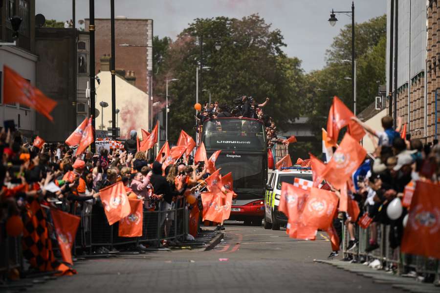 Luton Town football club players and staff celebrate with the Championship play-off trophy their promotion to the English Premier League during a parade through the streets of Luton