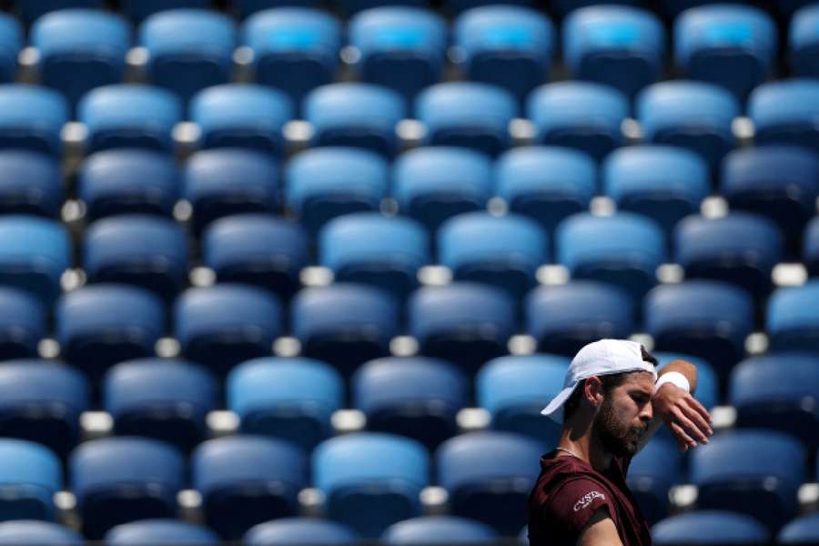 Karen Khachanov wipes his brow in front of empty seats during his third round match against Italy's Luciano Darderi