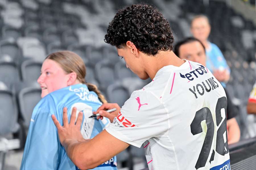 Melbourne City's Marcus Younis signs a shirt for a supporter.