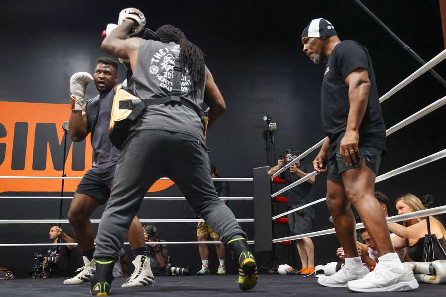 Cameroonian-French mixed martial arts star and boxer Francis Ngannou, left, spars with Dewey Cooper while former US boxer Mike Tyson (R) watches