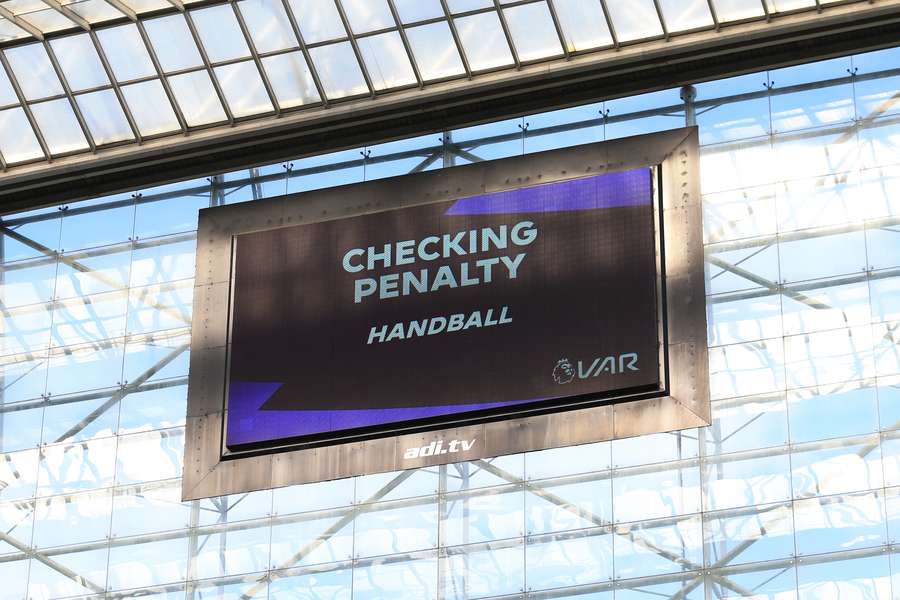 The big screen shows the VAR (Video Assistant Referee) in action, checking for a penalty for handball