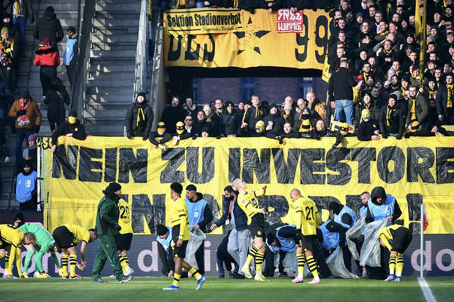 I giocatori del Dortmund raccolgono gli oggetti lanciati