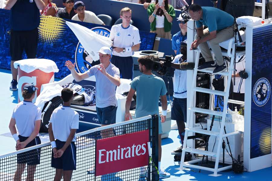 Jannik Sinner of Italy meets with Carlos Alcaraz of Spain and umpire Mohamed Lahyani to retire