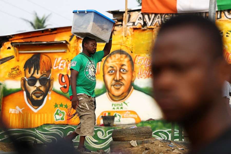 A man walks past murals depicting people wearing shirts of the Ivory Coast