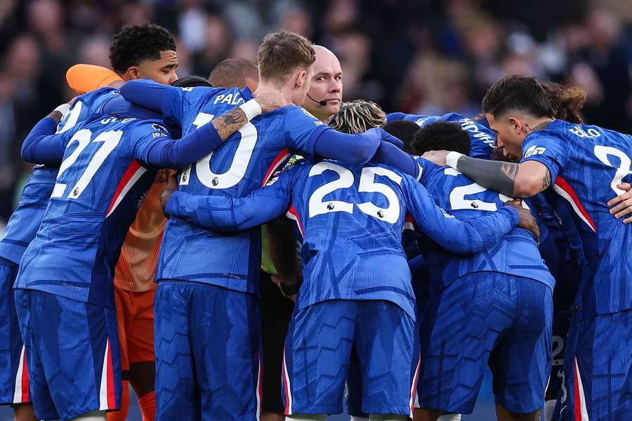 Chelsea players enter a huddle surrounding Referee Paul Tierney on the half way line 