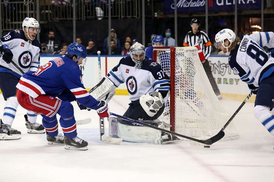 Jets goalie Connor Hellebuyck defends the goal against the Rangers