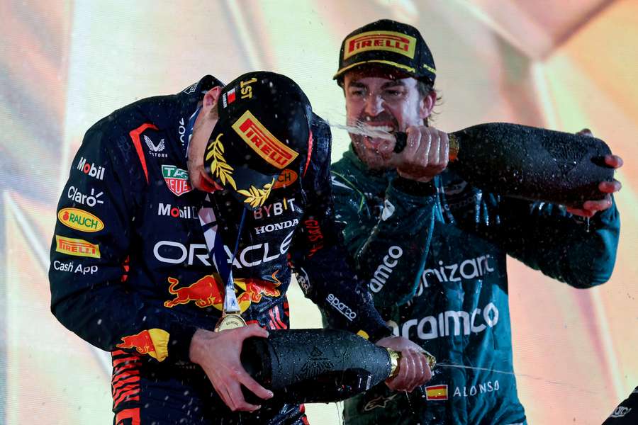 Aston Martin's Spanish driver Fernando Alonso sprays race winner Max Verstappen on the podium