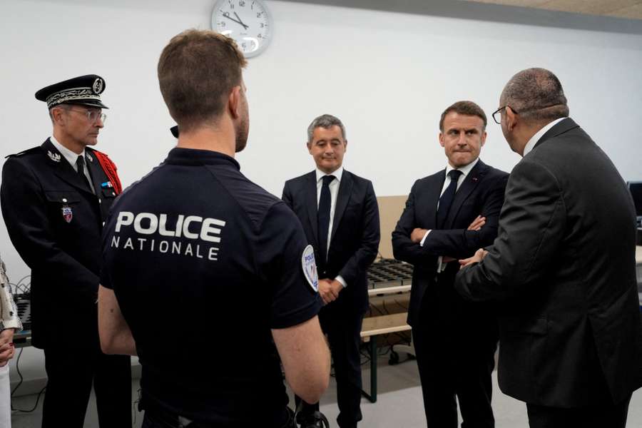 French President Emmanuel Macron and Gerald Darmanin listen to Paris police's Laurent Nunez on a visit to the police station of the Olympic village