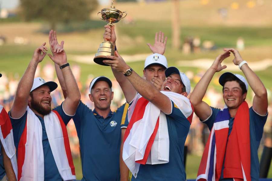 Rory McIlroy celebrates with the trophy and teammates during the presentation after winning the Ryder Cup