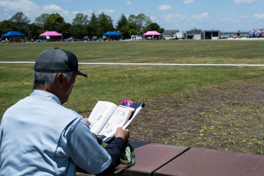 A Japan local reads a cricket rulebook whilst observing a T20 World Cup qualifier. A Japan local reads a cricket rulebook whilst observing a T20 World Cup qualifier.