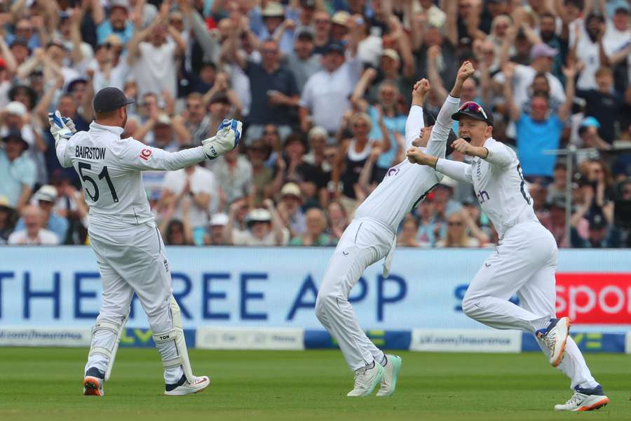 England's Jonny Bairstow (L) celebrates with Joe Root (C) and Ollie Pope (R) after taking a catch to dismiss Australia's Marnus Labuschagne