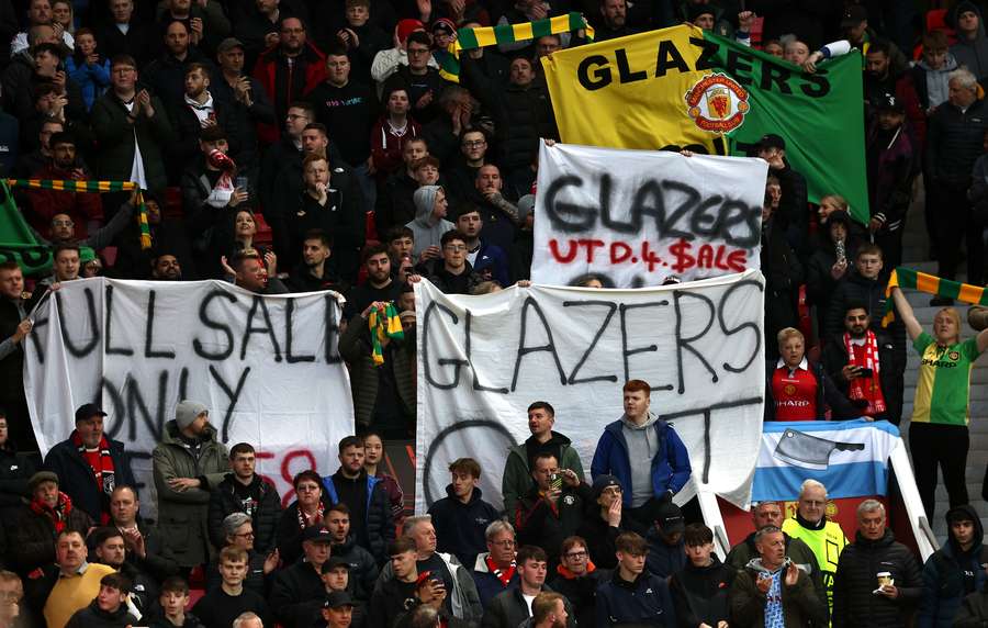 Manchester United fans hold banners calling for the club's owners, The Glazers, to leave