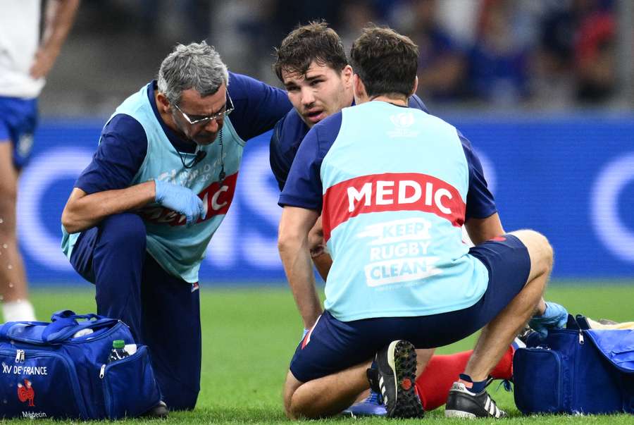 France scrum-half and captain Antoine Dupont (C) receives medical attention against during the Rugby World Cup match against Namibia