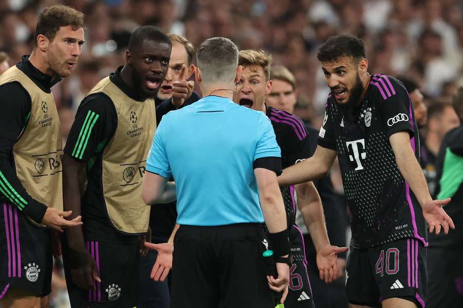 Jucătorii lui Bayern îl înconjoară pe arbitrul asistent pentru a îi cere explicații