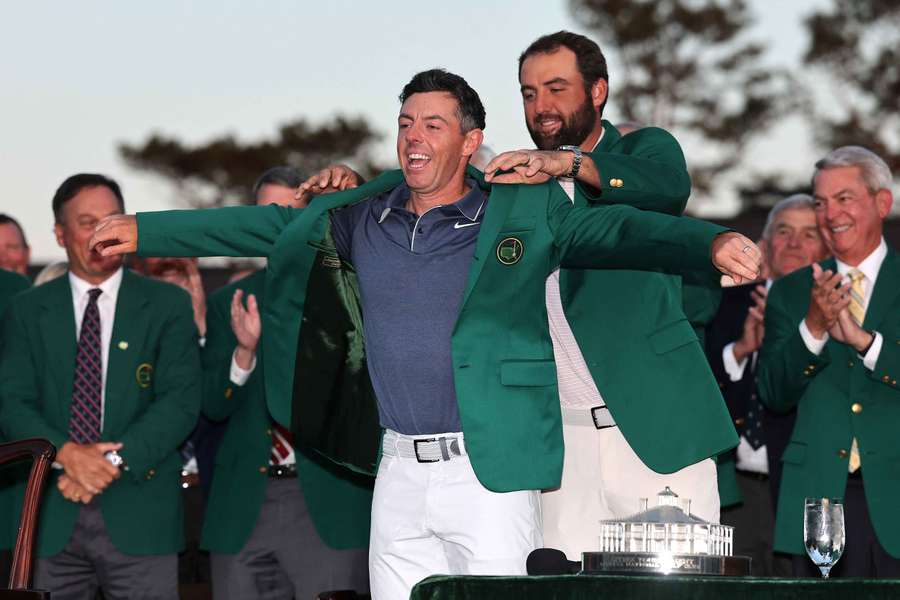 Rory McIlroy is awarded the green jacket by Scottie Scheffler after the final round of the 2025 Masters Tournament